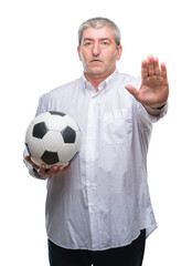 Canvas Print - Handsome senior man holding soccer football ball over isolated background with open hand doing stop sign with serious and confident expression, defense gesture