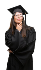 Sticker - Young hispanic woman wearing graduated cap and uniform looking confident at the camera with smile with crossed arms and hand raised on chin. Thinking positive.