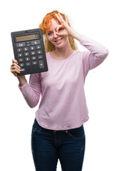 Wall Mural - Young redhead woman holding big calculator with happy face smiling doing ok sign with hand on eye looking through fingers