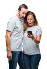 Wall Mural - Middle age hispanic couple texting message on smartphone ver isolated background scared in shock with a surprise face, afraid and excited with fear expression