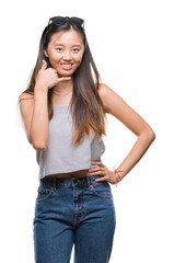 Sticker - Young asian woman wearing sunglasses over isolated background smiling doing phone gesture with hand and fingers like talking on the telephone. Communicating concepts.