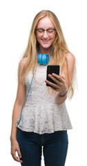 Canvas Print - Blonde teenager woman holding smartphone and wearing headphones with a happy face standing and smiling with a confident smile showing teeth