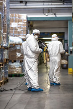 People In PPE Holding Sanitizing Machines In A Warehouse