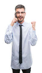 Canvas Print - Young business adult man talking on the phone screaming proud and celebrating victory and success very excited, cheering emotion