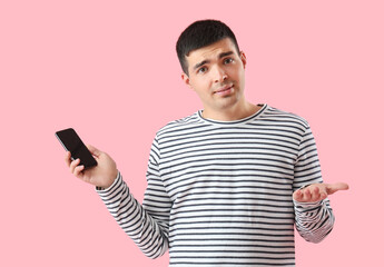 Poster - Helpless young man with smartphone on pink background