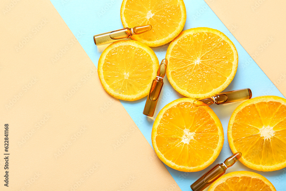 Ampoules with vitamin C and orange slices on colorful background