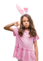 Wall Mural - Brunette hispanic girl wearing easter rabbit ears with angry face, negative sign showing dislike with thumbs down, rejection concept