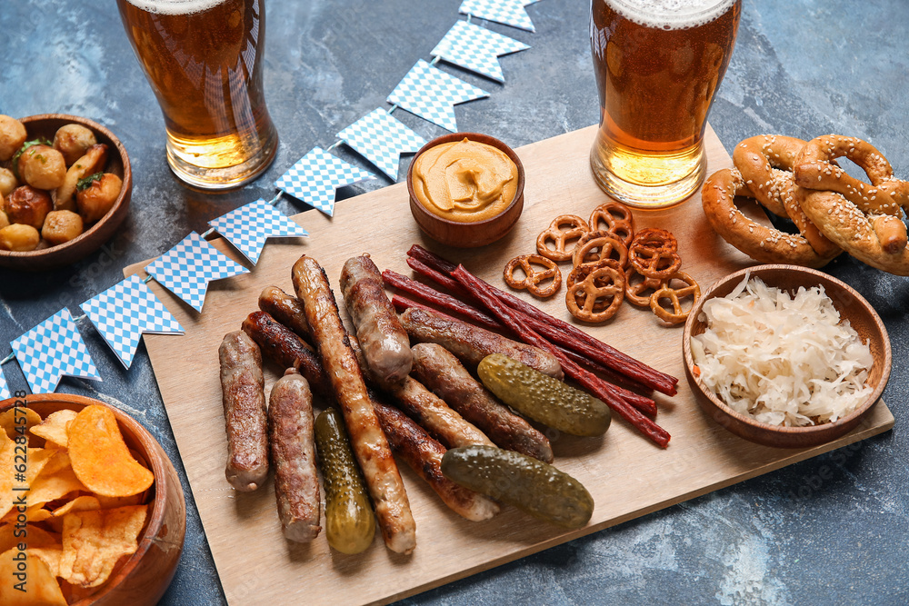 Wooden board with different snacks on blue background. Oktoberfest celebration