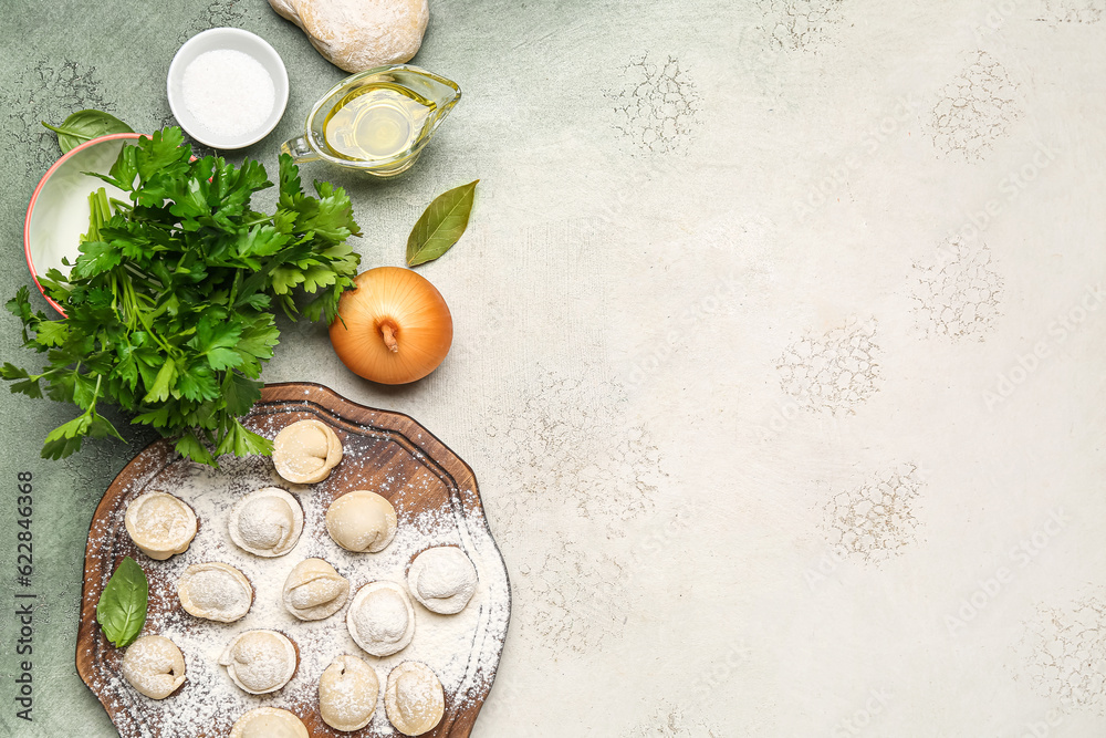 Wooden board with uncooked dumplings and ingredients on grunge background