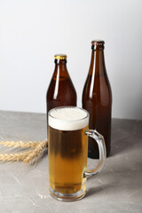 Mug of cold beer and bottles on table