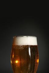 Glass of cold beer on dark background, closeup