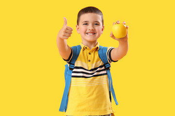 Poster - Little schoolboy with apple showing thumb-up on yellow background