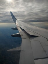 
The View From The Porthole Of The Plane - Gray Clouds, The Sea Below And The Wing Of The Plane Nearby