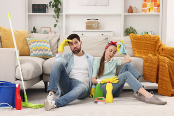 Canvas Print - Spring cleaning. Tired couple with detergents and mop in living room