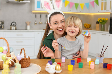 Sticker - Mother and her son painting Easter eggs at table in kitchen