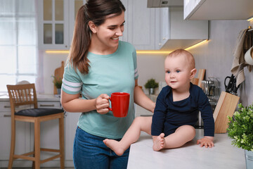 Canvas Print - Happy young woman and her cute little baby spending time together in kitchen