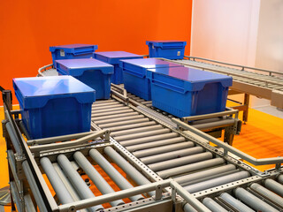 Poster - Mechanical conveyor. Production tape with plastic boxes. Conveyor in shop. Mechanical production belt for sorting goods. Metal roller conveyor. Production line to speed up sorting of goods