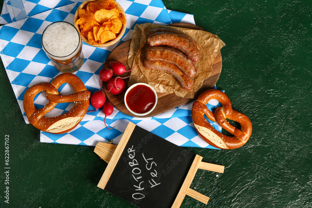 Glass of cold beer and different snacks on green background. Oktoberfest celebration