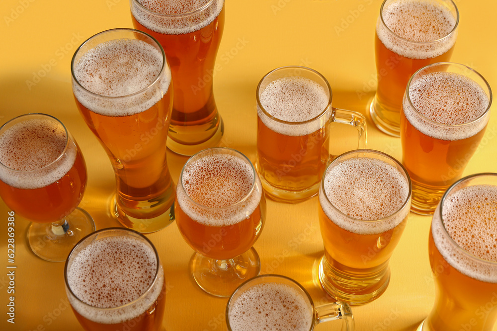 Glasses and mugs of cold beer on yellow background. Oktoberfest celebration