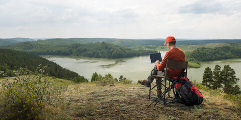 man working outdoors with laptop. banner with copy space. remote freelancer work in nature.