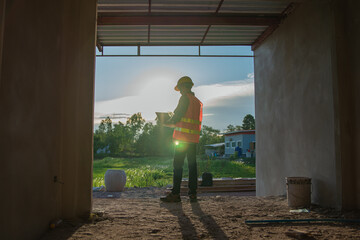 construction worker supervising construction site work and sunset background