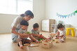 © amanaimages - おもちゃで遊ぶ子供たちと女性の保育士