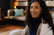 © Wavebreak Media - Portrait of happy biracial woman sitting on sofa in living room