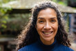 © Wavebreak Media - Portrait of happy biracial woman with dark curly hair smiling in garden