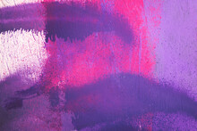 Purple Paint Strokes And Smudges On An Pink Painted Wall Background. Abstract Wall Surface With Part Of Graffiti. Colorful Drips, Flows, Streaks Of Paint And Paint Sprays
