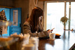 © amanaimages - カフェのカウンターでスマホを触っている女性
