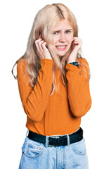 Poster - Young caucasian woman wearing casual clothes covering ears with fingers with annoyed expression for the noise of loud music. deaf concept.