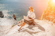 © svetograph - Business woman on nature in white shirt and black skirt. She works with an iPad in the open air with a beautiful view of the sea. The concept of remote work.