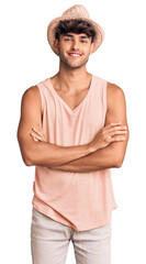 Poster - Young hispanic man wearing summer hat happy face smiling with crossed arms looking at the camera. positive person.