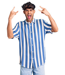 Poster - Young hispanic man wearing casual clothes shouting with crazy expression doing rock symbol with hands up. music star. heavy music concept.