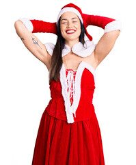 Sticker - Young beautiful caucasian woman wearing santa claus costume relaxing and stretching, arms and hands behind head and neck smiling happy