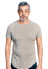 Canvas Print - Middle age hispanic with grey hair wearing casual grey t shirt puffing cheeks with funny face. mouth inflated with air, crazy expression.