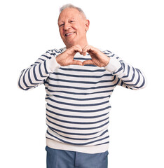 Canvas Print - Senior handsome grey-haired man wearing casual striped sweater smiling in love showing heart symbol and shape with hands. romantic concept.