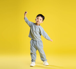 full body image of boy posing on a yellow background.