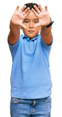 Sticker - Little boy hispanic kid wearing casual clothes doing frame using hands palms and fingers, camera perspective