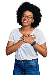 Poster - Young african american woman wearing casual white t shirt smiling with hands on chest with closed eyes and grateful gesture on face. health concept.