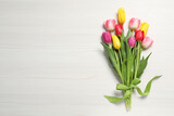 Fototapeta Tulipany - Beautiful tulips on white wooden table, flat lay. Space for text