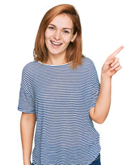 Wall Mural - Young caucasian woman wearing casual clothes with a big smile on face, pointing with hand and finger to the side looking at the camera.