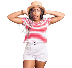 Sticker - Young african american woman with braids wearing summer hat crazy and scared with hands on head, afraid and surprised of shock with open mouth