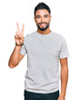 © Krakenimages.com - Young man with beard wearing casual grey tshirt showing and pointing up with fingers number two while smiling confident and happy.