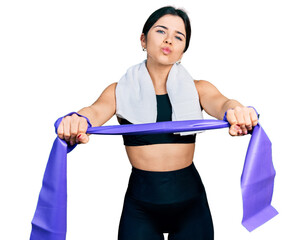 Poster - Young brunette woman with blue eyes training arm resistance with elastic arm bands looking at the camera blowing a kiss being lovely and sexy. love expression.