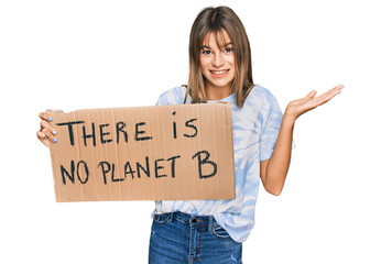 Teenager caucasian girl holding there is no planet b banner celebrating victory with happy smile and winner expression with raised hands