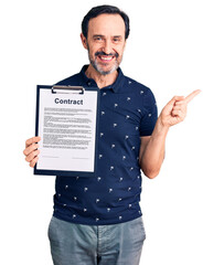 Sticker - Middle age handsome man holding clipboard with contract document smiling happy pointing with hand and finger to the side