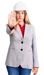 Canvas Print - Beautiful young woman wearing architect hardhat doing stop sing with palm of the hand. warning expression with negative and serious gesture on the face.