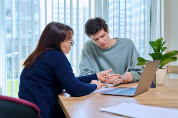 Woman teacher talking helping testing male teenage student