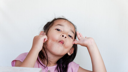 Cute little girl making a funny face at the camera pursing her lips, annoyed face.